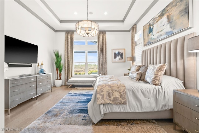 bedroom featuring a chandelier, light wood-type flooring, and a raised ceiling