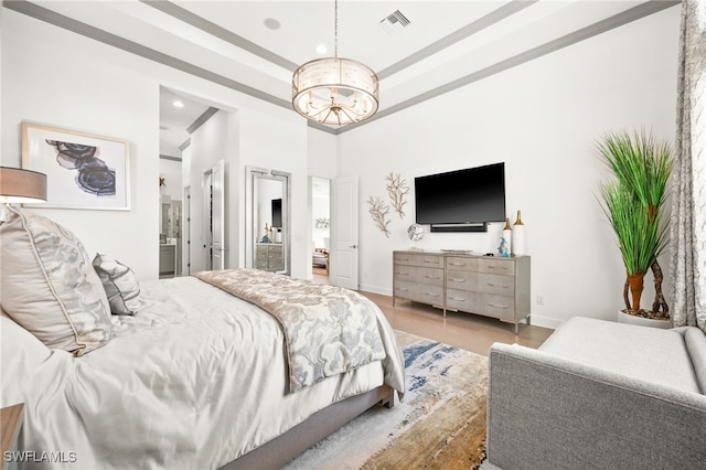 bedroom featuring a chandelier, light hardwood / wood-style flooring, and ensuite bath