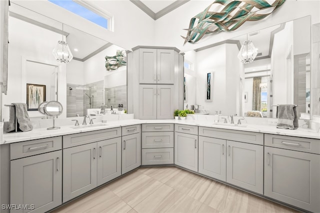 bathroom with a tile shower, vanity, an inviting chandelier, and ornamental molding