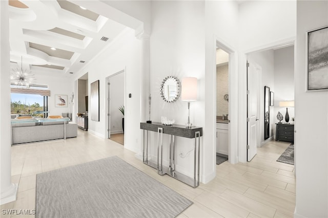 hall featuring beam ceiling, ornamental molding, coffered ceiling, and a high ceiling