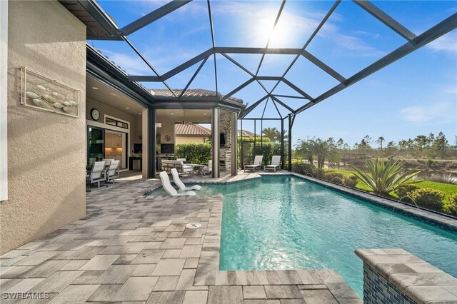 view of pool featuring pool water feature, a patio, glass enclosure, and ceiling fan