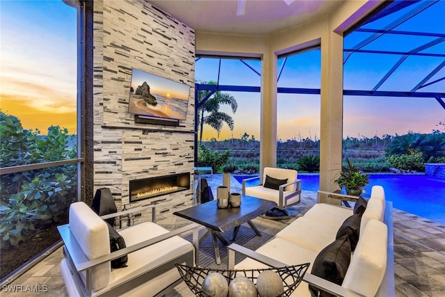 view of patio / terrace with an outdoor living space with a fireplace, pool water feature, and a lanai