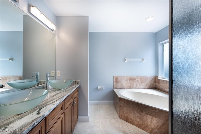 bathroom with tiled bath, vanity, and tile patterned flooring