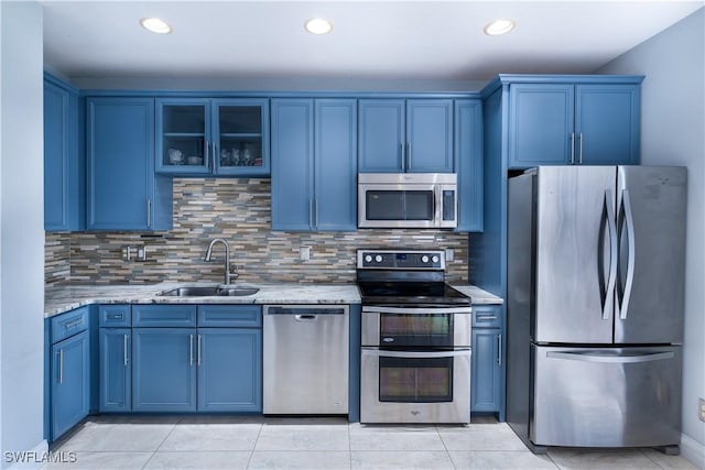 kitchen with backsplash, sink, light stone countertops, appliances with stainless steel finishes, and blue cabinetry