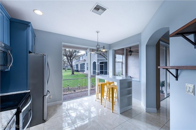 kitchen featuring hanging light fixtures, a kitchen breakfast bar, stainless steel appliances, light tile patterned floors, and blue cabinets