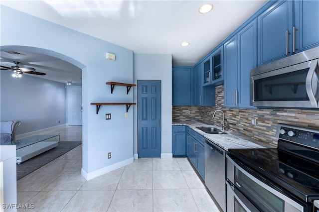 kitchen featuring ceiling fan, stainless steel appliances, decorative backsplash, blue cabinets, and sink