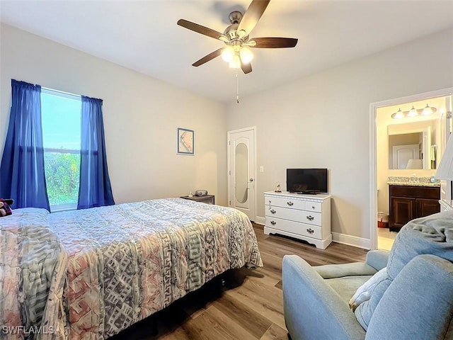 bedroom with ceiling fan, connected bathroom, and light hardwood / wood-style flooring