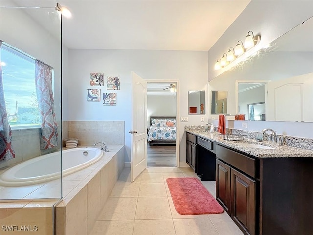 bathroom with tile patterned flooring, a relaxing tiled tub, ceiling fan, and vanity