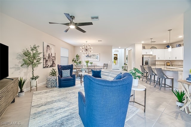 tiled living room with sink and ceiling fan with notable chandelier