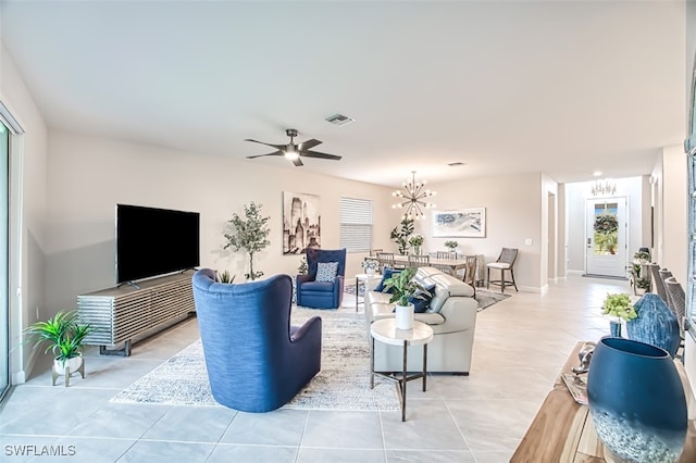 tiled living room with ceiling fan with notable chandelier