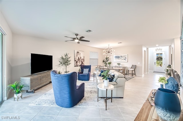 living area with light tile patterned flooring, visible vents, a healthy amount of sunlight, and ceiling fan with notable chandelier