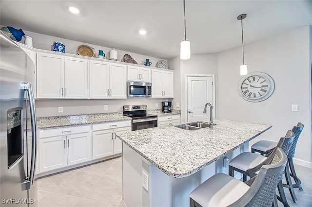 kitchen with sink, a center island with sink, pendant lighting, stainless steel appliances, and white cabinets