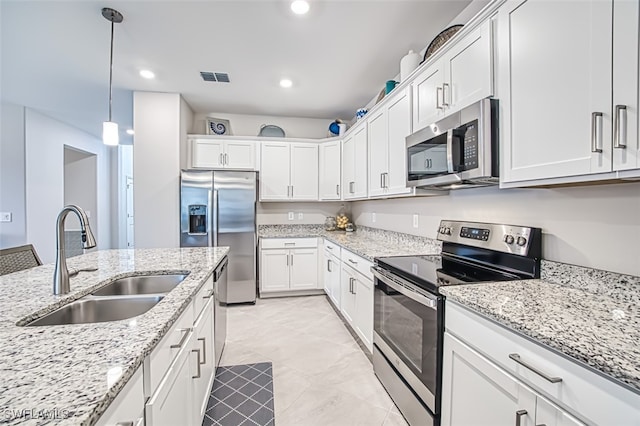 kitchen featuring a sink, appliances with stainless steel finishes, decorative light fixtures, white cabinetry, and visible vents