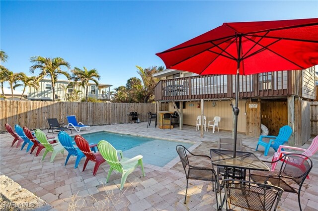 view of swimming pool featuring a patio, exterior bar, and a deck