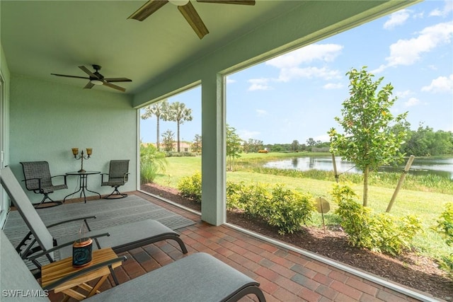 sunroom featuring ceiling fan and a water view