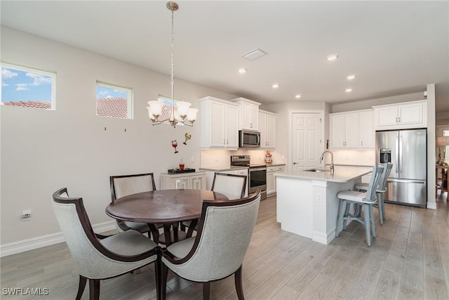 dining room with light hardwood / wood-style flooring, an inviting chandelier, and sink