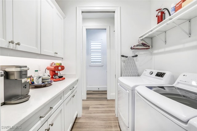 laundry room featuring washer and dryer, light wood-type flooring, and cabinets