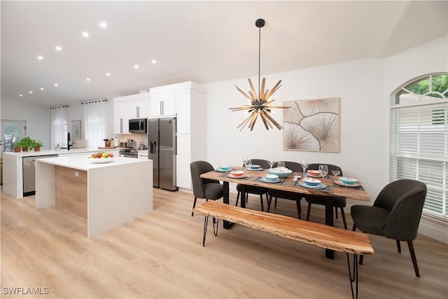 kitchen with an inviting chandelier, white cabinets, decorative light fixtures, a kitchen island, and appliances with stainless steel finishes