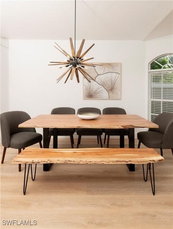 dining area with light hardwood / wood-style flooring and an inviting chandelier