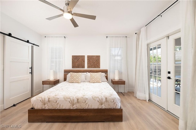 bedroom featuring access to outside, french doors, ceiling fan, a barn door, and light wood-type flooring