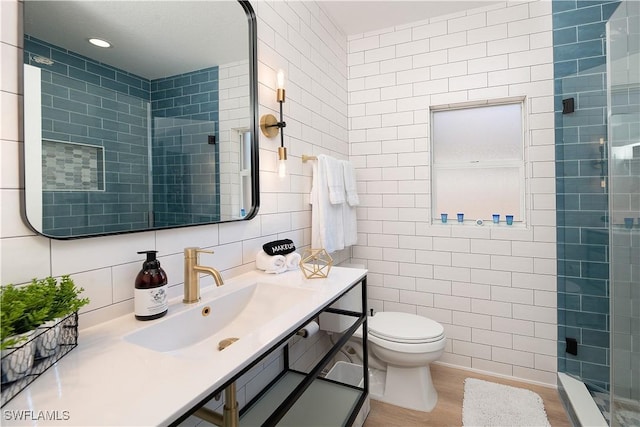 bathroom with vanity, a shower, decorative backsplash, toilet, and tile walls