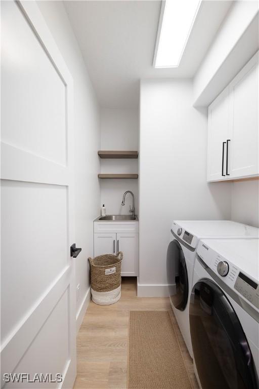 washroom with cabinets, separate washer and dryer, sink, and light hardwood / wood-style flooring