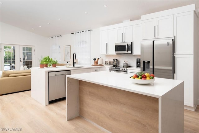 kitchen with a kitchen island, sink, appliances with stainless steel finishes, and french doors