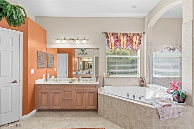 bathroom featuring a relaxing tiled tub, vanity, and tile patterned flooring