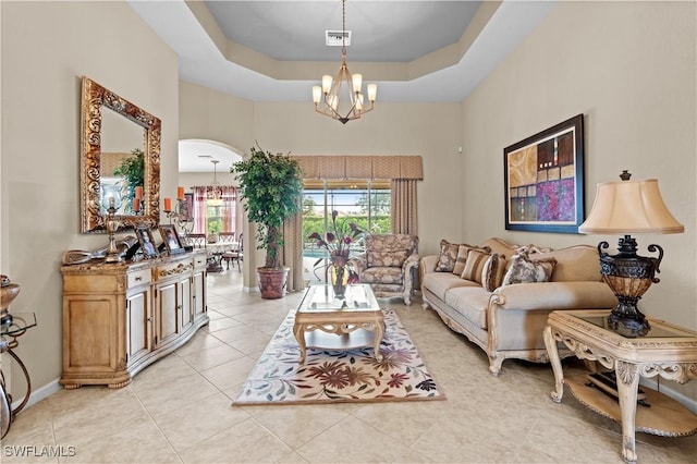 tiled living room with a tray ceiling and a notable chandelier