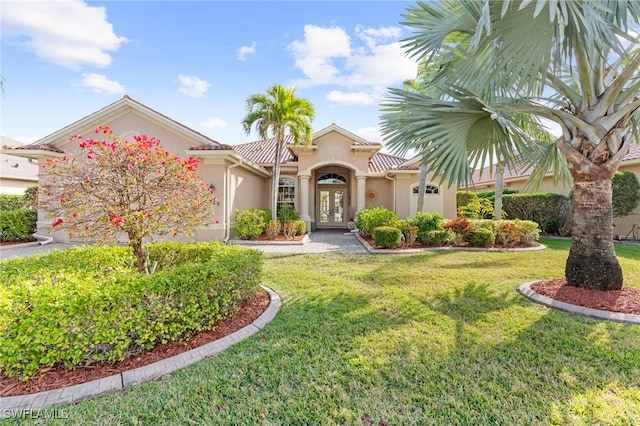 mediterranean / spanish-style home with a front lawn and french doors