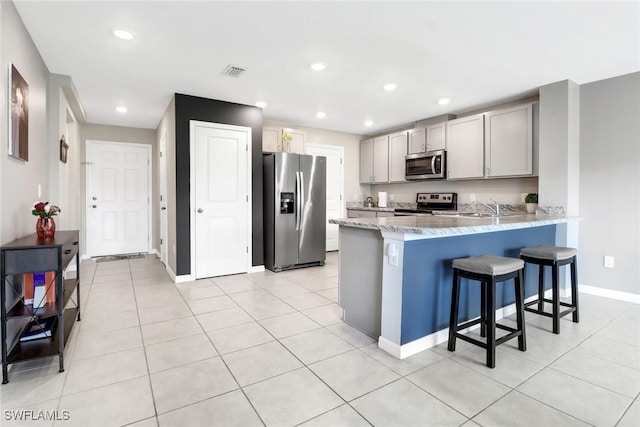 kitchen featuring a breakfast bar, sink, gray cabinets, kitchen peninsula, and stainless steel appliances