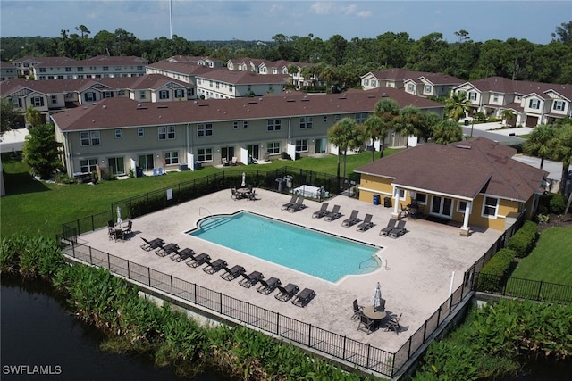 view of pool featuring a patio, a water view, and a lawn