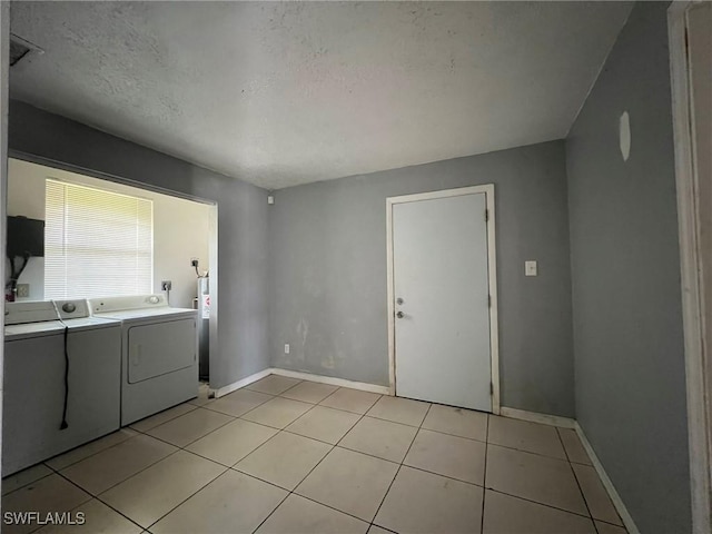 washroom featuring a textured ceiling, light tile patterned flooring, and independent washer and dryer