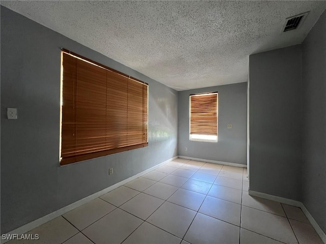 tiled spare room with a textured ceiling