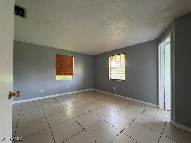 tiled empty room with a textured ceiling