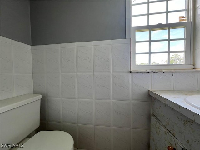 bathroom featuring toilet, tile walls, and vanity