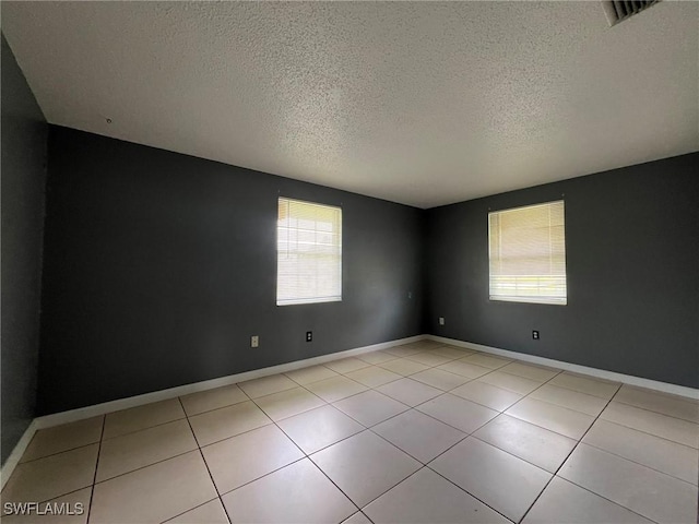 spare room featuring light tile patterned floors, plenty of natural light, and a textured ceiling