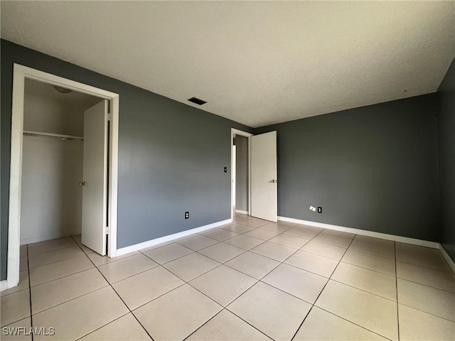 unfurnished bedroom featuring a textured ceiling, a closet, and light tile patterned floors