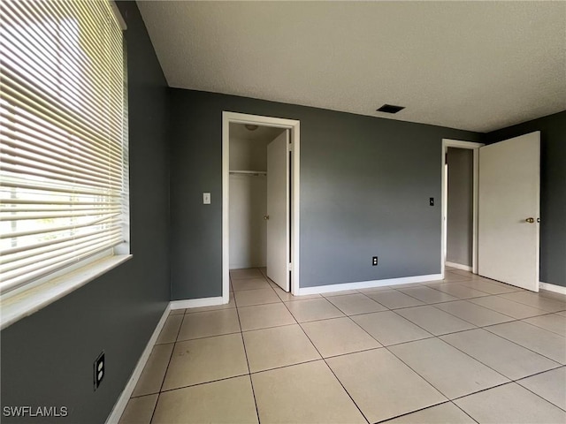 unfurnished bedroom with a spacious closet, a closet, and light tile patterned floors