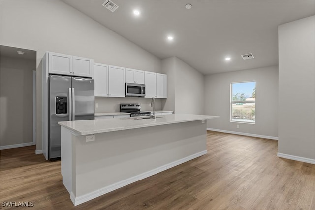 kitchen with stainless steel appliances, white cabinets, an island with sink, and sink