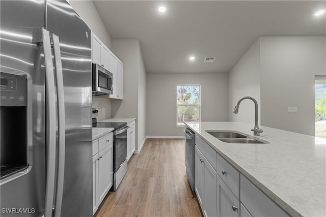 kitchen featuring sink, stainless steel appliances, white cabinetry, and light hardwood / wood-style flooring