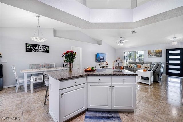 kitchen with white cabinets, ceiling fan, a kitchen island, and decorative light fixtures