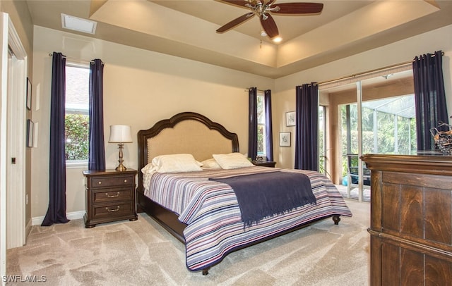 carpeted bedroom with ceiling fan, multiple windows, and a raised ceiling