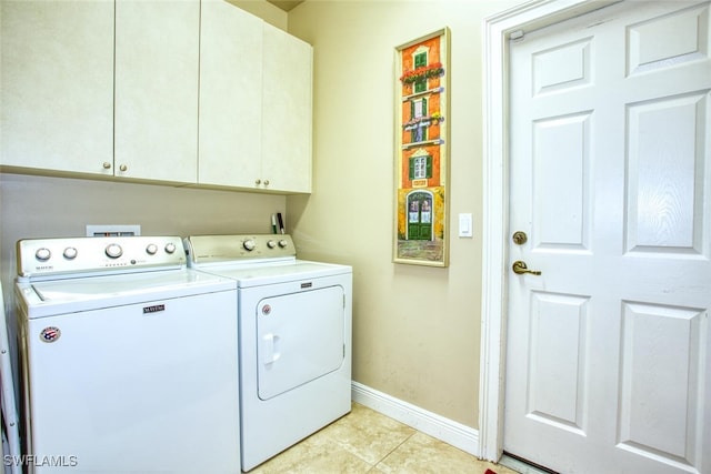 clothes washing area featuring washing machine and dryer, light tile patterned flooring, and cabinets