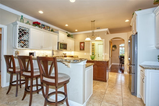 kitchen featuring stone countertops, pendant lighting, white cabinets, and stainless steel appliances