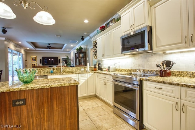 kitchen featuring decorative light fixtures, stainless steel appliances, sink, light tile patterned flooring, and a tray ceiling