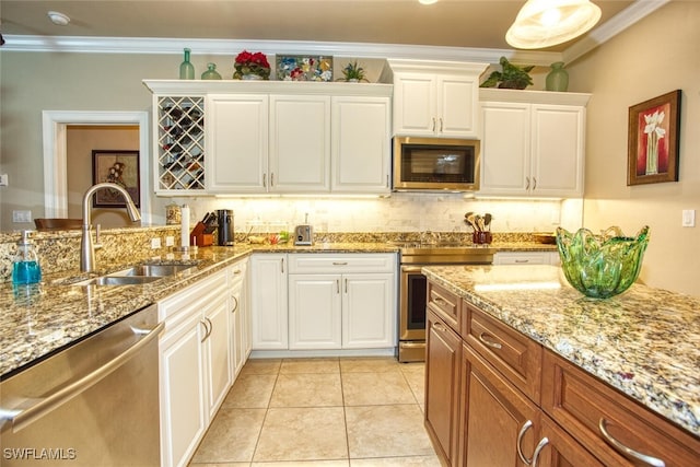 kitchen with light tile patterned floors, stainless steel appliances, ornamental molding, white cabinets, and sink