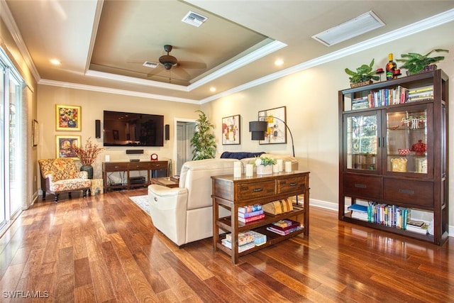 living room featuring dark hardwood / wood-style flooring, crown molding, and a tray ceiling