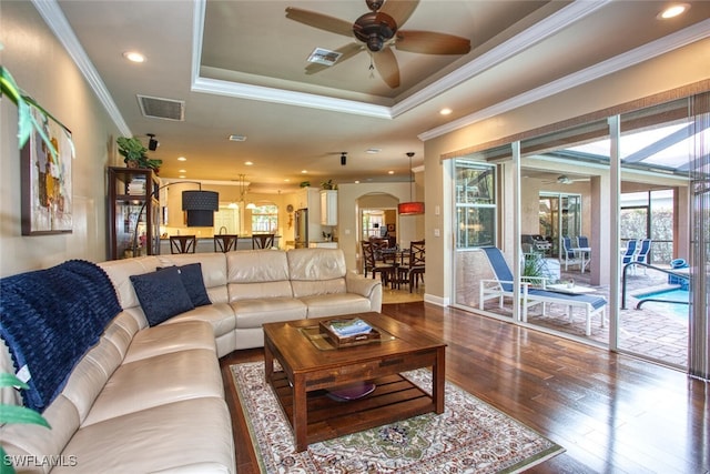 living room with a raised ceiling, ceiling fan, ornamental molding, and hardwood / wood-style floors