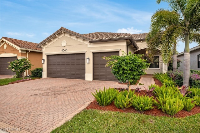 4063 Aspen Chase Dr, Naples, FL 34119 - mediterranean / spanish-style home featuring decorative driveway, a garage, stucco siding, and a tiled roof